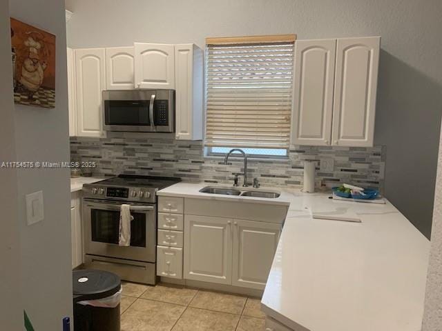 kitchen with light tile patterned floors, white cabinets, appliances with stainless steel finishes, and a sink