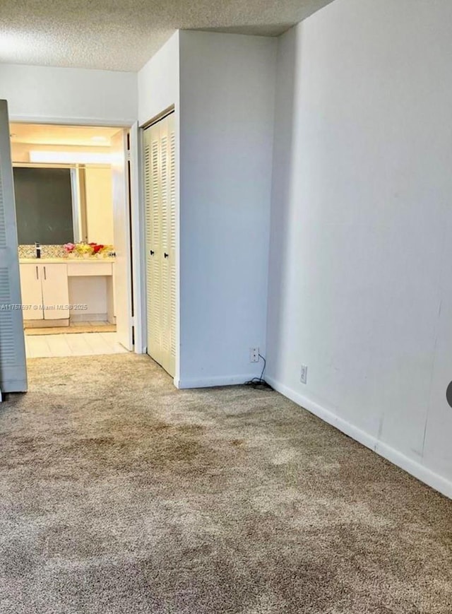 empty room with a textured ceiling, carpet floors, and baseboards