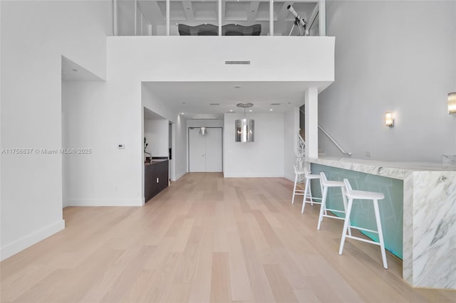 entrance foyer with baseboards, visible vents, wood finished floors, a high ceiling, and stairs