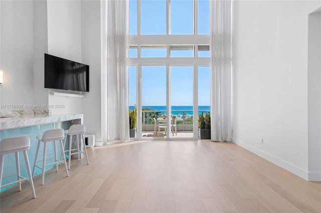 unfurnished living room with wood finished floors, a towering ceiling, and baseboards