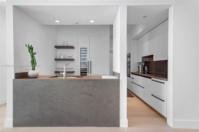 kitchen featuring light wood-type flooring, white cabinets, a sink, and modern cabinets