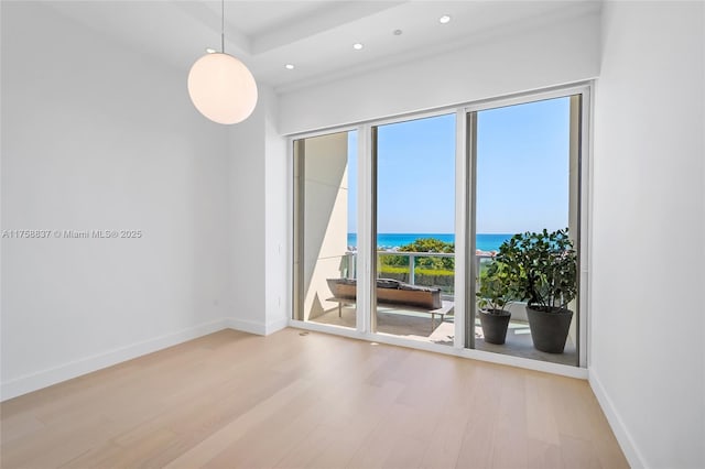 empty room with light wood-type flooring, a water view, baseboards, and recessed lighting