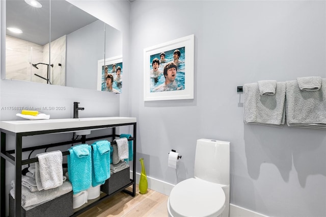 bathroom featuring a stall shower, baseboards, toilet, wood finished floors, and vanity