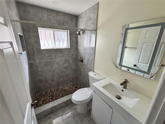 full bathroom with vanity, toilet, and a tile shower