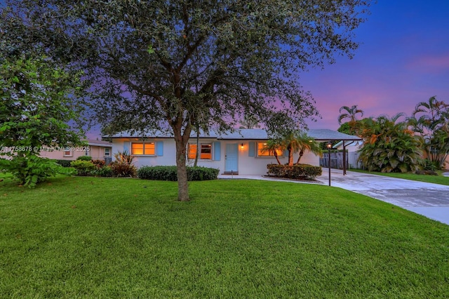 ranch-style home with fence, concrete driveway, stucco siding, a carport, and a front yard