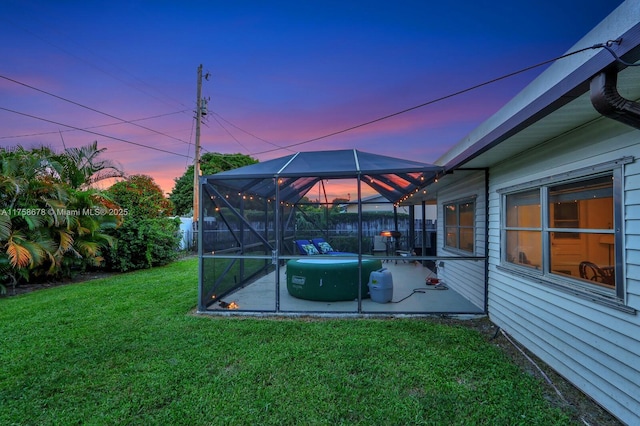 yard at dusk featuring a lanai and a patio