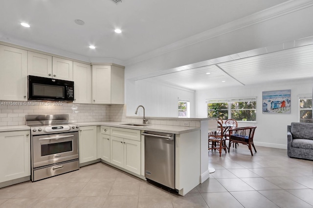 kitchen with appliances with stainless steel finishes, light countertops, a sink, and tasteful backsplash