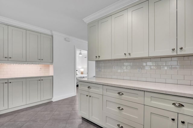 kitchen with ornamental molding, light tile patterned flooring, light stone counters, and tasteful backsplash