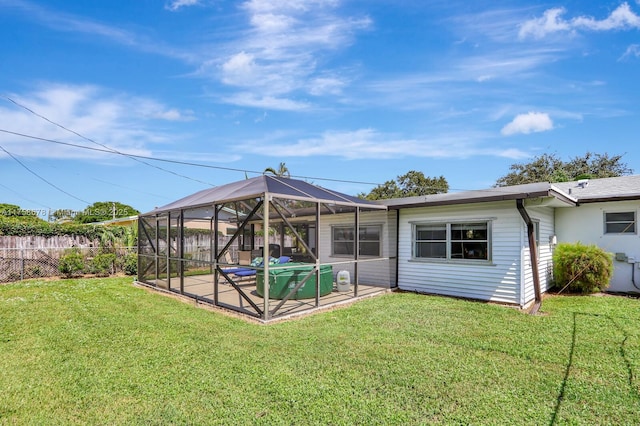 back of property with a patio, a pool, a lawn, fence, and a lanai