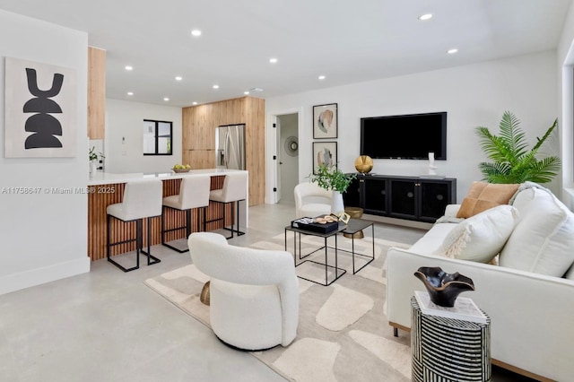 living room with concrete flooring, recessed lighting, and baseboards