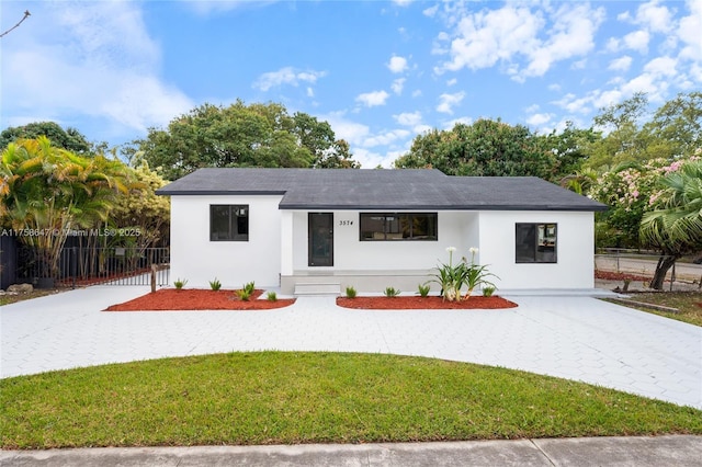 view of front of home with decorative driveway, a front yard, fence, and stucco siding