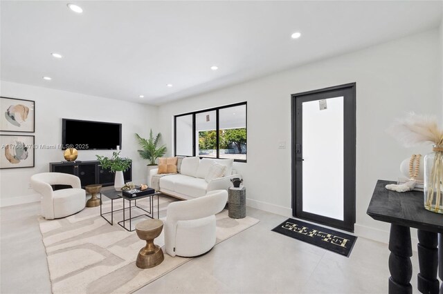 living area with concrete floors, baseboards, and recessed lighting