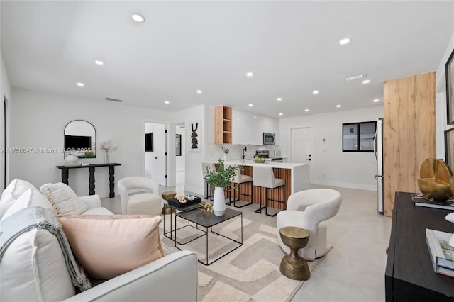 living area featuring baseboards, concrete floors, visible vents, and recessed lighting