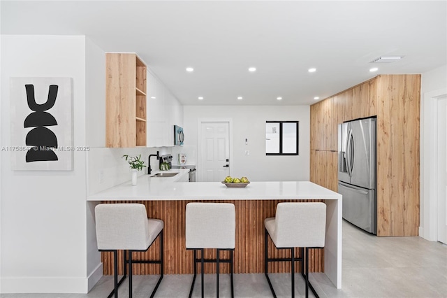 kitchen featuring modern cabinets, appliances with stainless steel finishes, a breakfast bar area, a peninsula, and open shelves