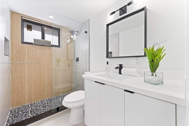 full bathroom with tiled shower, vanity, and toilet