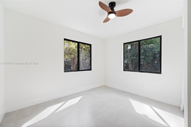 unfurnished room featuring finished concrete floors, baseboards, and a ceiling fan