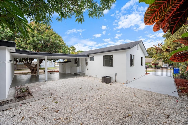 back of property featuring a gate, central AC unit, fence, and stucco siding