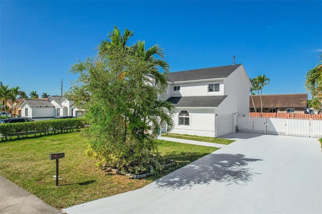 view of front of house with driveway, an attached garage, a gate, a front yard, and stucco siding