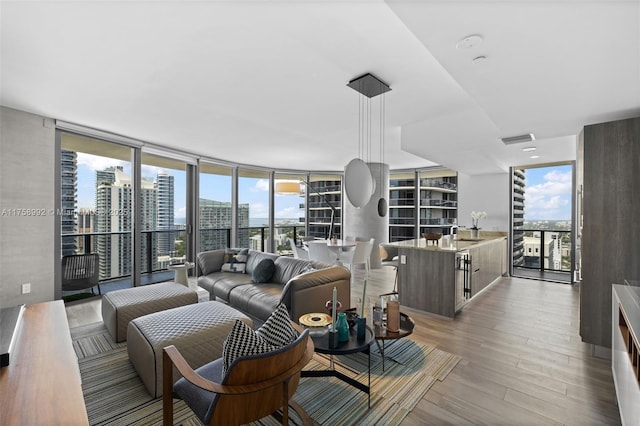 living room with a wall of windows, light wood-type flooring, a wealth of natural light, and a city view