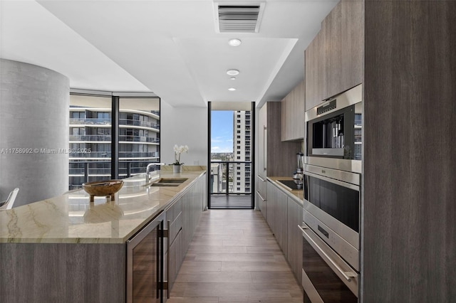 kitchen with beverage cooler, modern cabinets, visible vents, and a sink