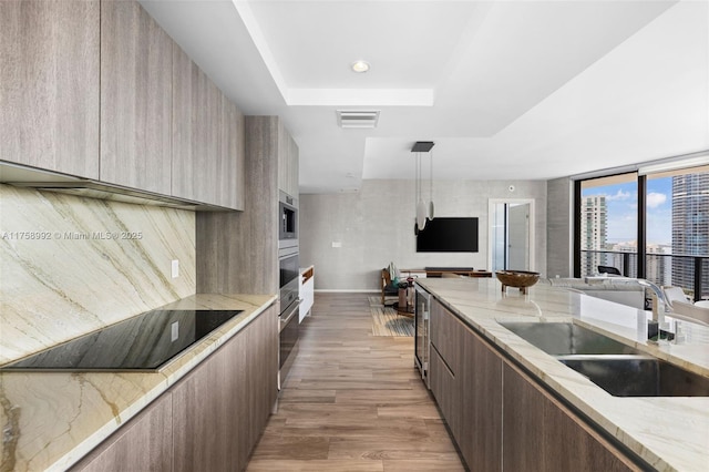 kitchen with black electric stovetop, visible vents, a sink, modern cabinets, and oven