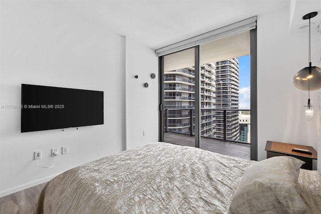 bedroom with floor to ceiling windows and wood finished floors