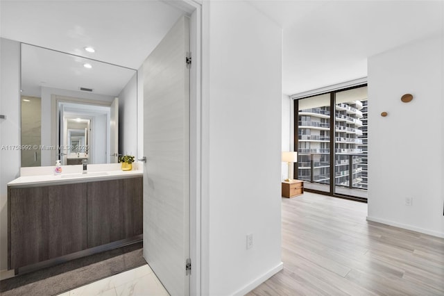 bathroom with recessed lighting, vanity, baseboards, visible vents, and a wall of windows