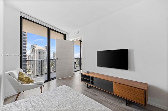 living area with floor to ceiling windows, baseboards, and wood finished floors