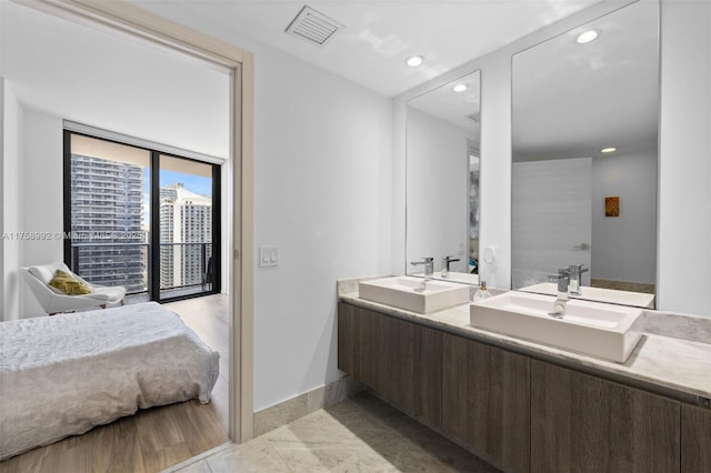 full bath featuring double vanity, a sink, visible vents, and baseboards