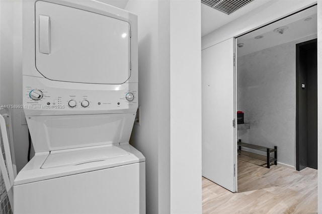 laundry room with stacked washer and dryer, light wood-type flooring, laundry area, and visible vents