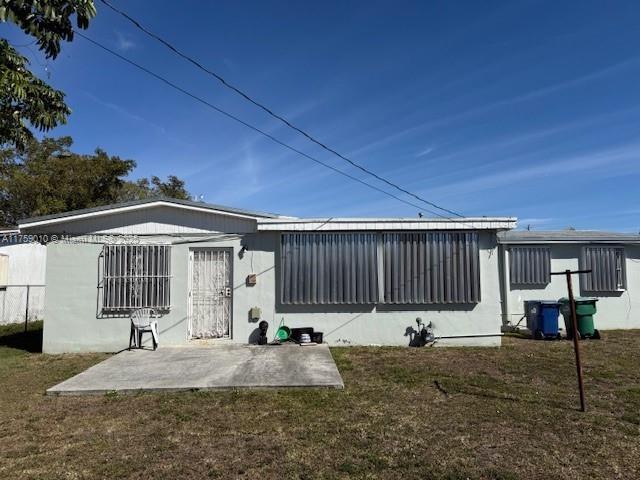 back of house with a patio and a lawn