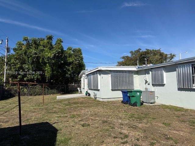 view of property exterior featuring fence, central AC, and a yard