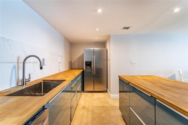 kitchen featuring butcher block counters, visible vents, appliances with stainless steel finishes, and a sink