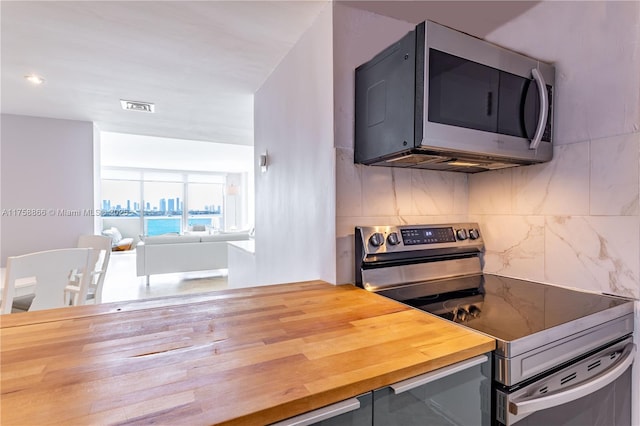 kitchen with butcher block counters, visible vents, gray cabinetry, decorative backsplash, and appliances with stainless steel finishes