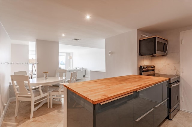 kitchen featuring gray cabinetry, stainless steel appliances, butcher block countertops, visible vents, and tasteful backsplash