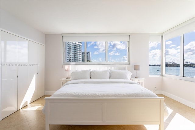 bedroom featuring light tile patterned floors, baseboards, and a closet