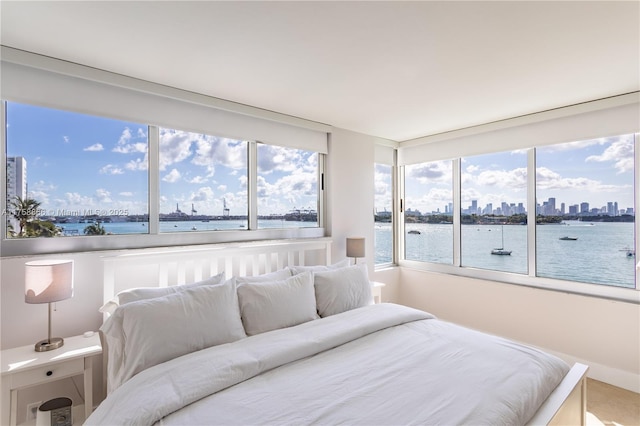 bedroom with a water view, multiple windows, and a city view