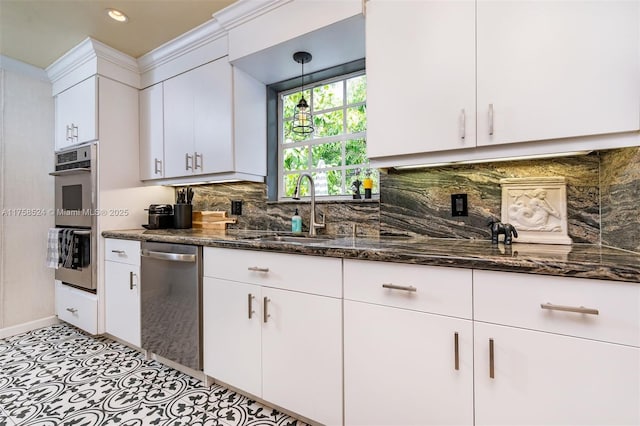 kitchen featuring a sink, dark stone countertops, stainless steel appliances, white cabinets, and decorative backsplash