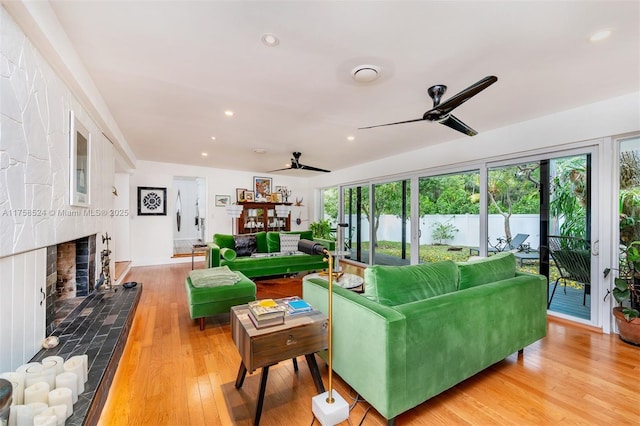 living area with recessed lighting, light wood-style flooring, a ceiling fan, and a tile fireplace