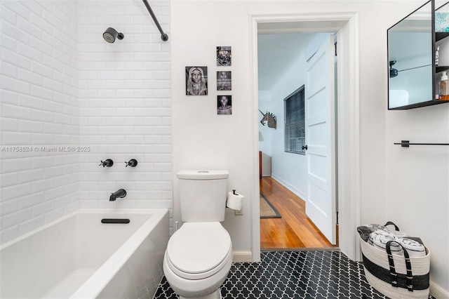 bathroom featuring bathtub / shower combination, toilet, wood finished floors, and baseboards