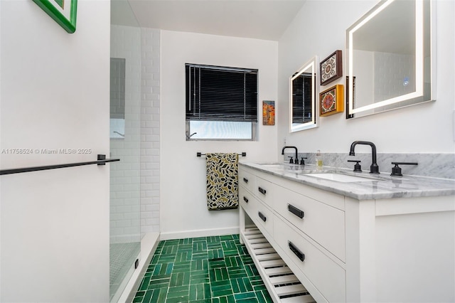 full bathroom featuring a sink, baseboards, tiled shower, and double vanity