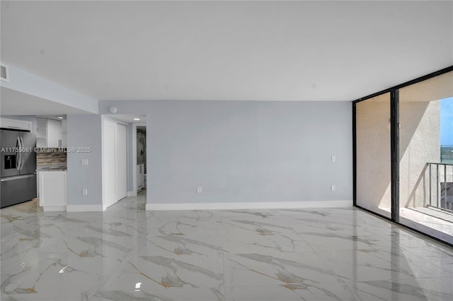 unfurnished living room featuring expansive windows, marble finish floor, visible vents, and baseboards