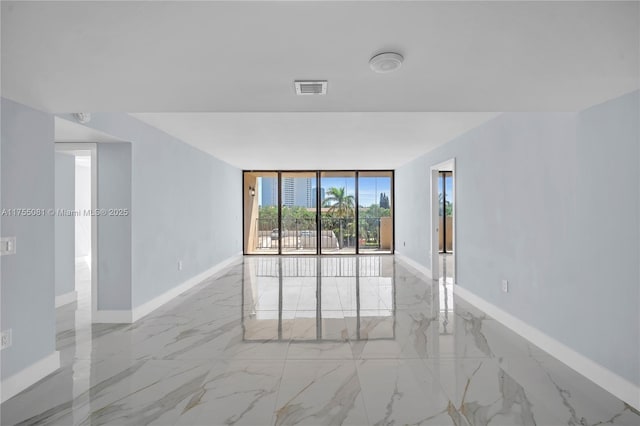 empty room featuring marble finish floor, visible vents, floor to ceiling windows, and baseboards