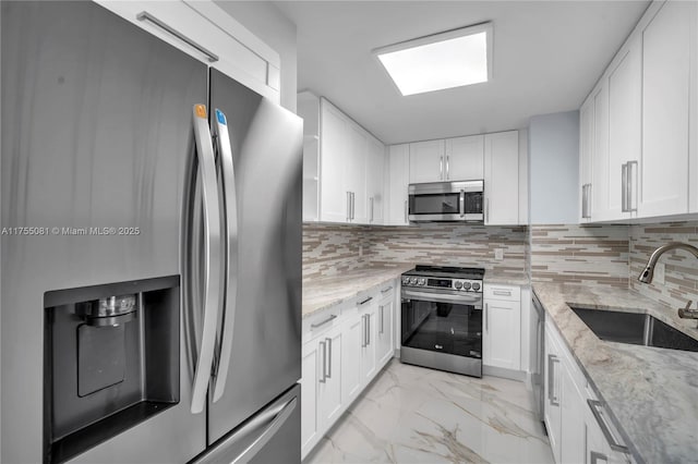 kitchen with white cabinets, marble finish floor, stainless steel appliances, and a sink