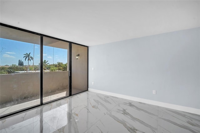 unfurnished room with marble finish floor, baseboards, and a wall of windows