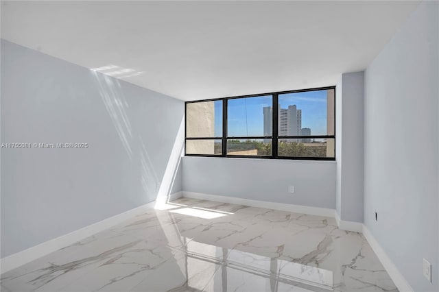 spare room featuring marble finish floor and baseboards