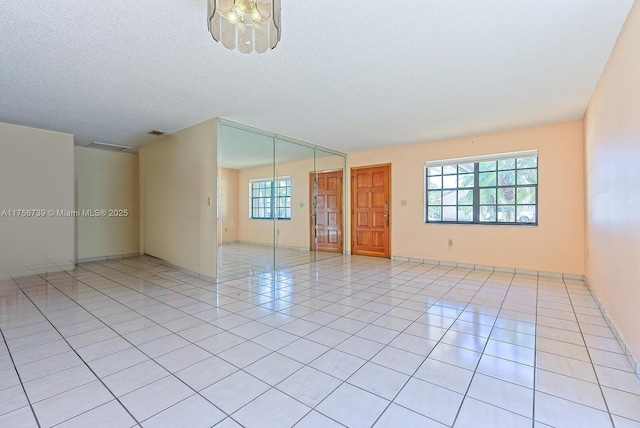 unfurnished room featuring light tile patterned floors, visible vents, and a textured ceiling