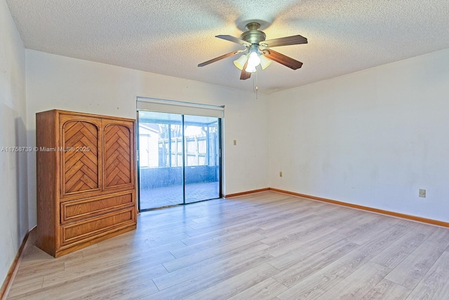 unfurnished room with a ceiling fan, light wood-style flooring, baseboards, and a textured ceiling