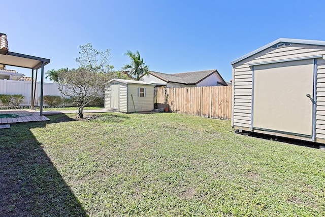 view of yard featuring a shed, a fenced backyard, and an outbuilding