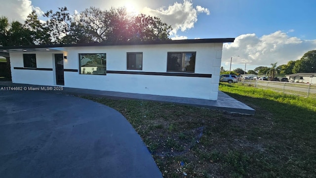 view of property exterior featuring stucco siding, fence, and a yard